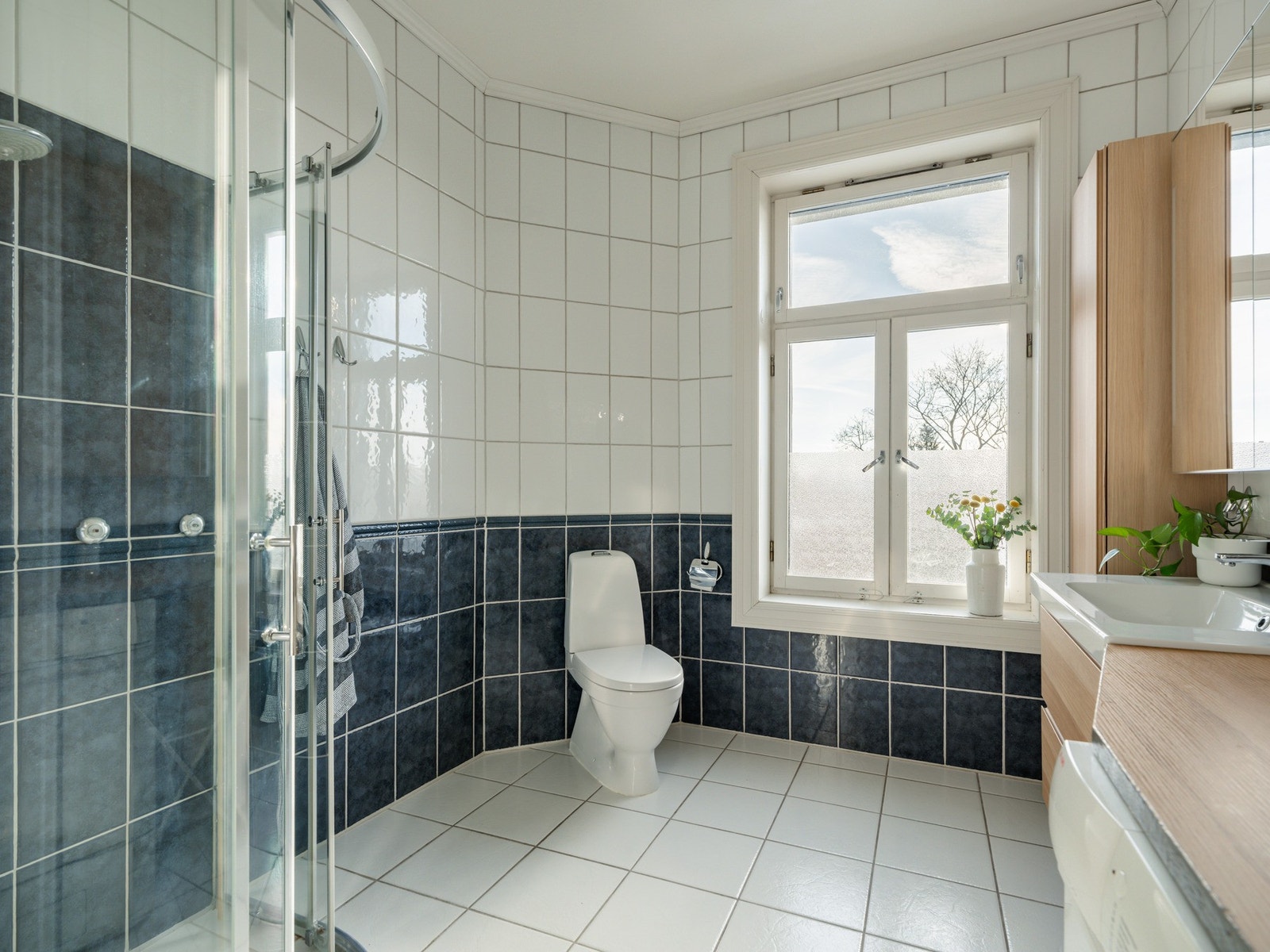 Badet er innredet med gulvstående toalett, dusjhjørne og baderomsinnredning. Galleribilde