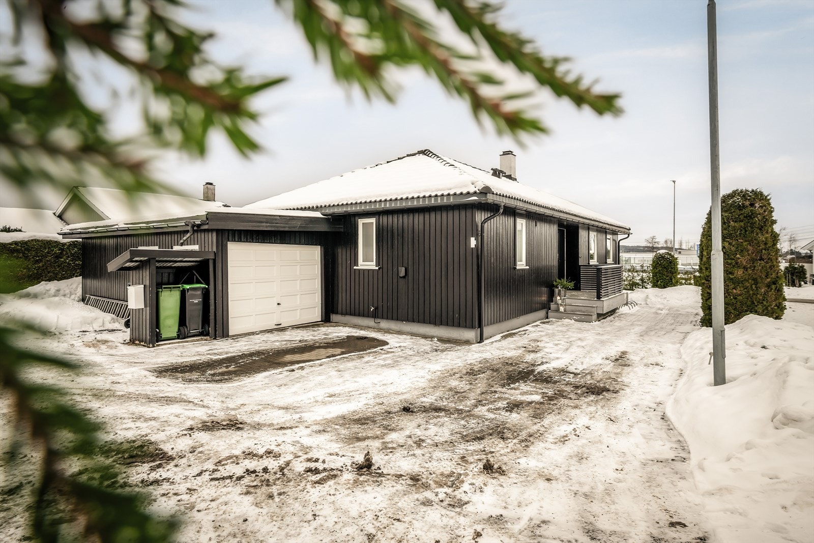 Parkering gjøres i enkelgarasje og på egen tomt. Det er montert elbil-lader på husvegg. Galleribilde