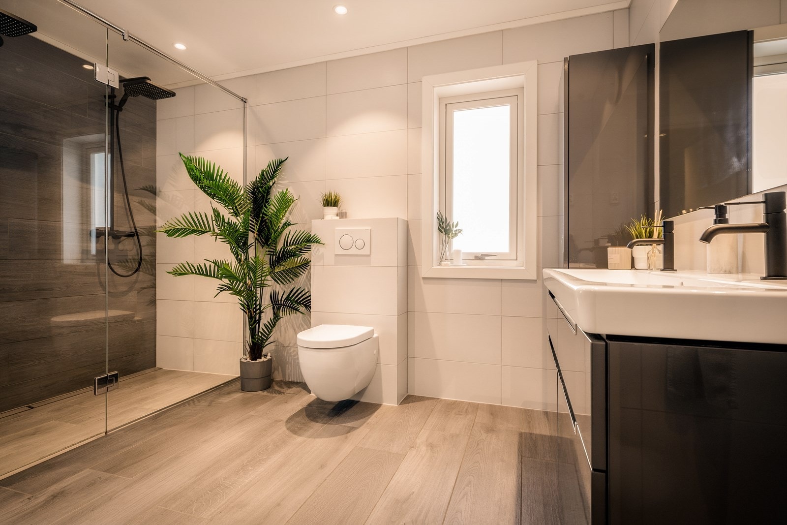 Badet har gulvvarme og utstrakt bruk av downlights i himling. Praktisk vegghengt wc og dobbelservant. Galleribilde