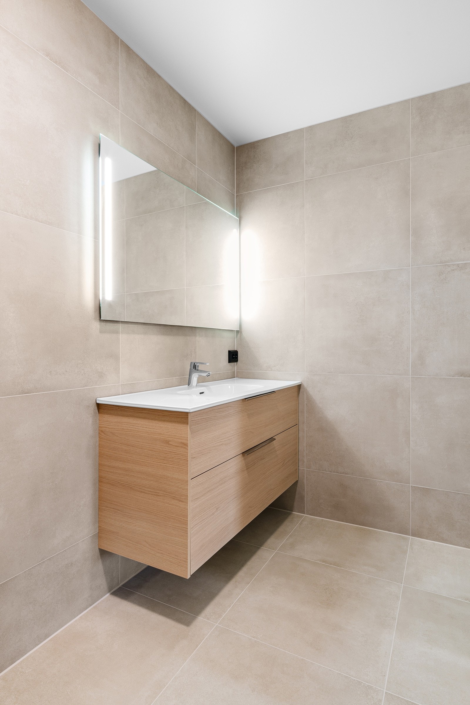 Rommet er innredet med servant på skuffeseksjon og speil med belysning. Videre er badet utstyrt med vegghengt toalett og dusj. Galleribilde