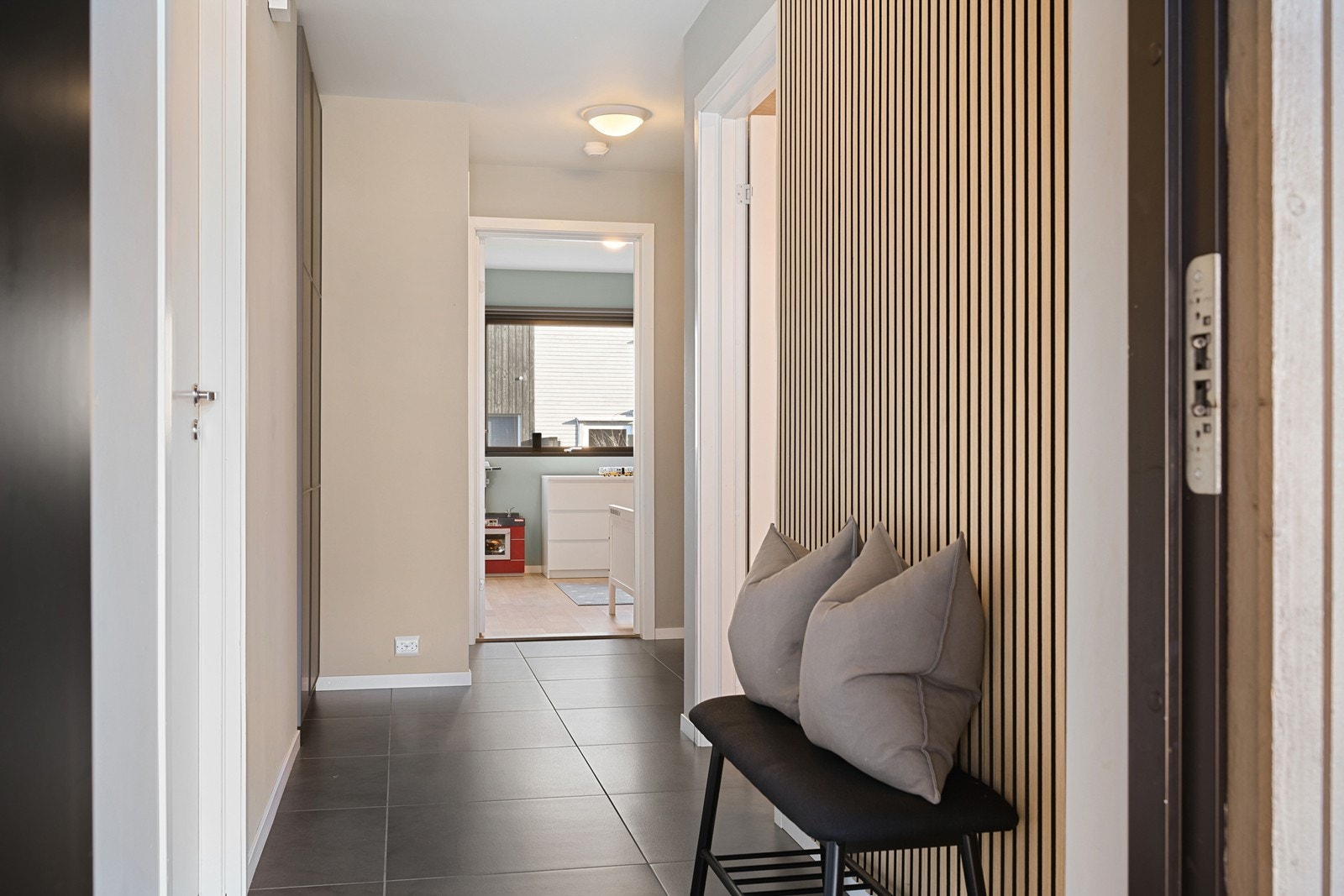 Entré med dekorativ spilevegg og flislagt gulv med varmekabler Galleribilde