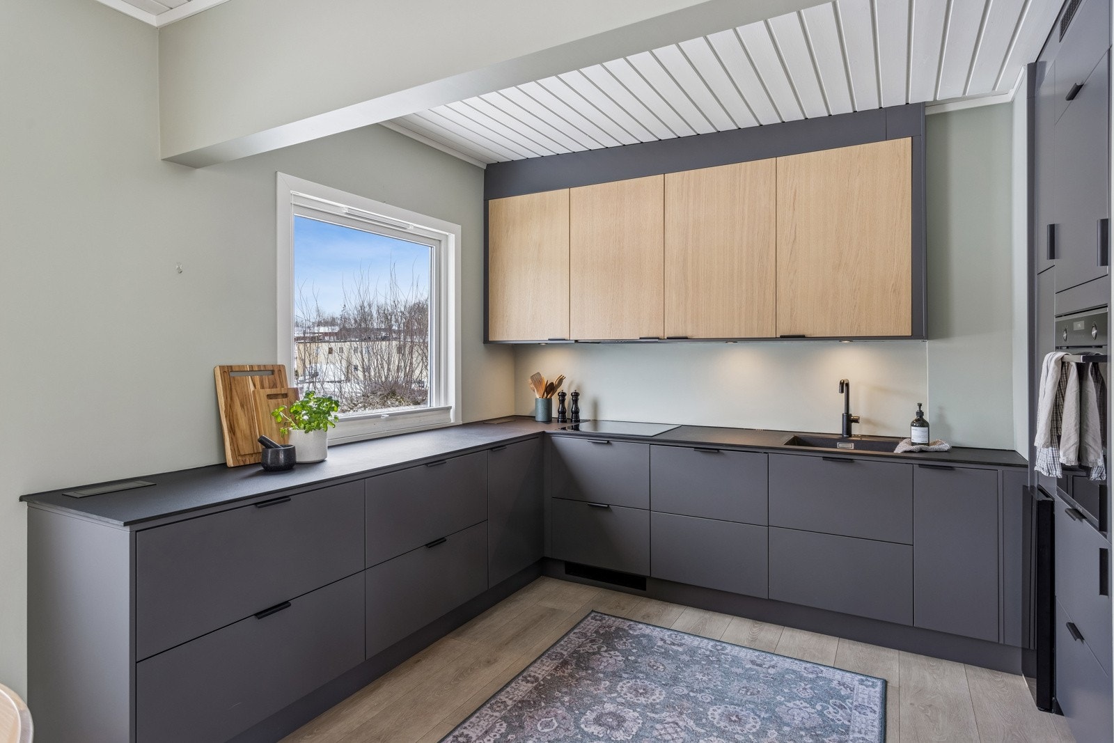 Kjøkkeninnredning med slette fronter og takhøy innredning, benkeplate i laminat og underlimt servant. Galleribilde