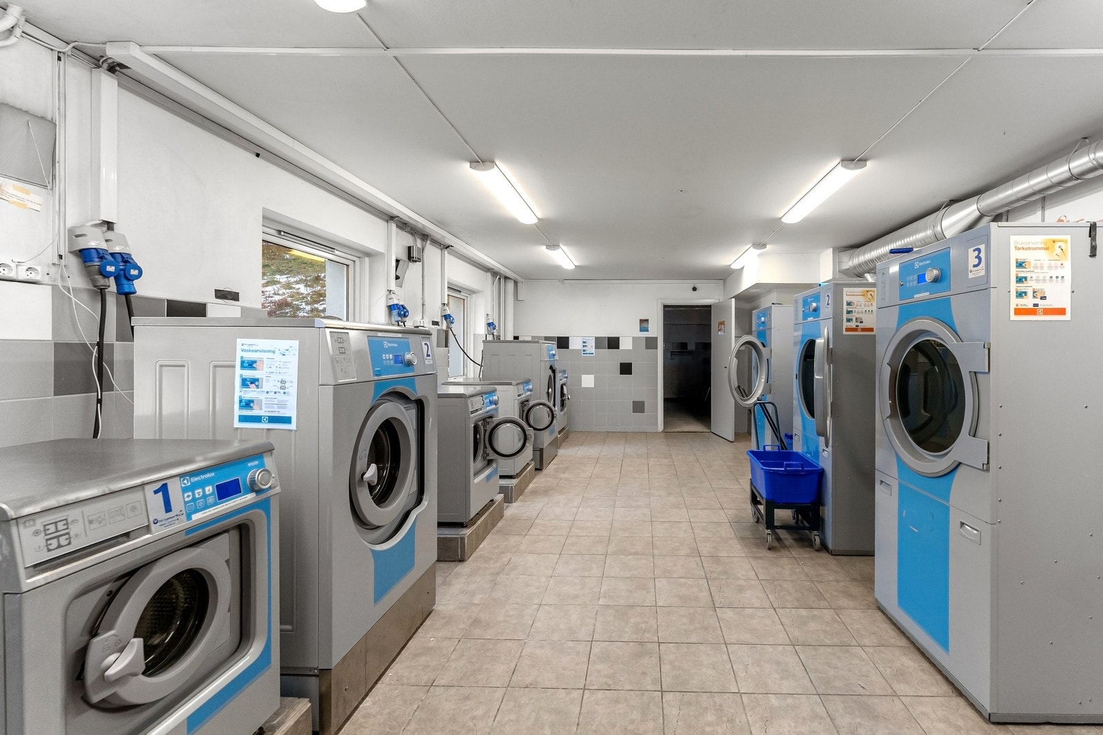 Fellesvaskeri i borettslaget med flere maskiner og tørketromler. Galleribilde