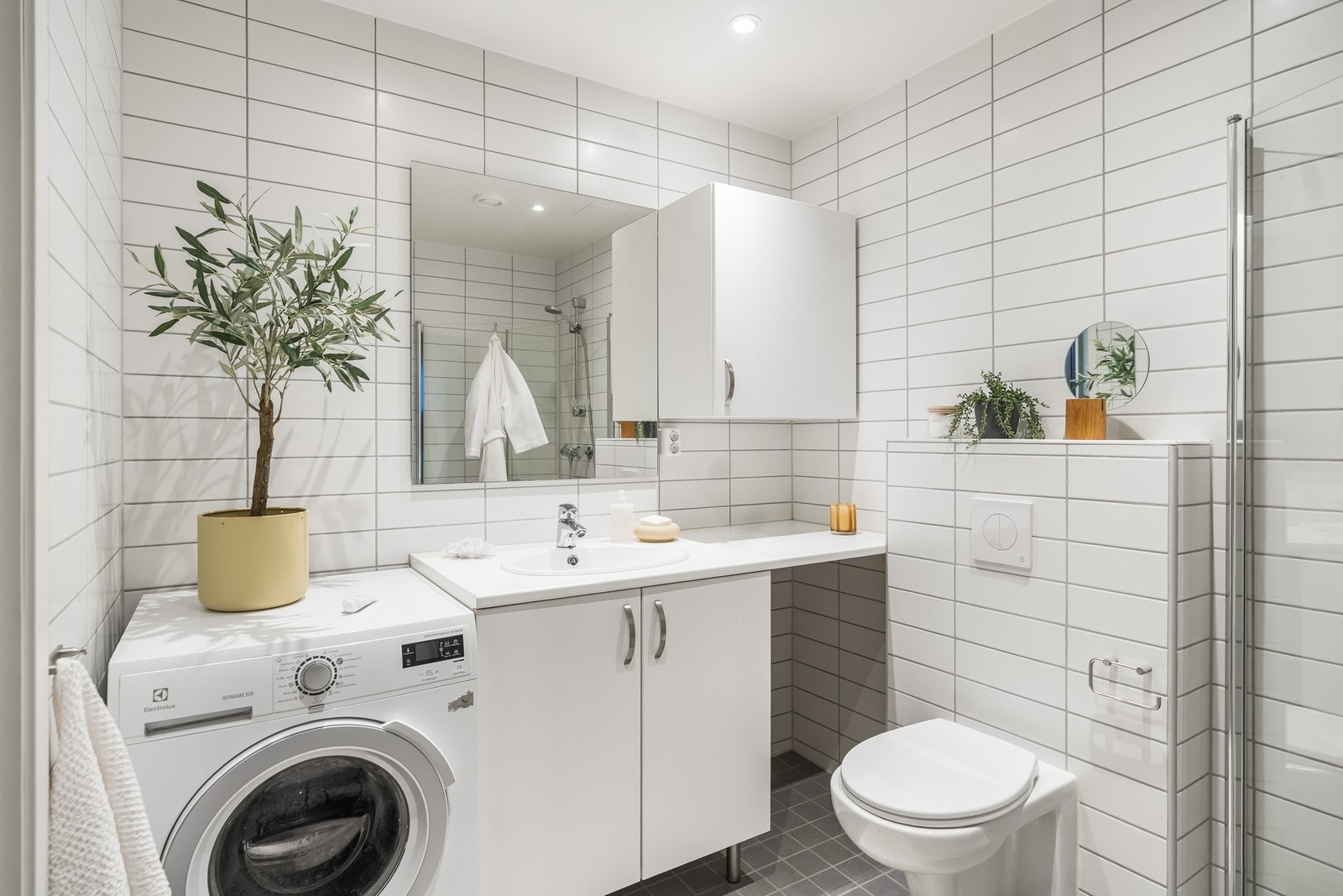 Innredningen består av servant med underskap, speil med sideskap, vegghengt WC og dusjsone med innfellbare dusjdører av herdet glass Galleribilde