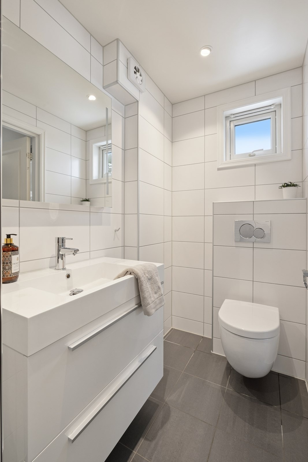 Badet i 1. etasje er utstyrt med dusj med glassvegger, vegghengt klosett med innebygget sisterne og servantinnredning med speil og belysning. Galleribilde