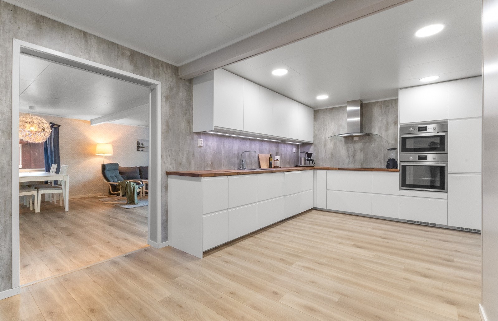 Lekkert kjøkken - IKEA med integrerte hvitevarer. Laminerte skrog med slette fronter. Heltre benkeplater. Kjøkkenplater på vegger over benkeplater. Integrert koketopp, steikeovn, mikro-ovn/ steikeovn 2 og kjøl-/fryseskap. Oppvaskkum og skyllekum av stål. Galleribilde