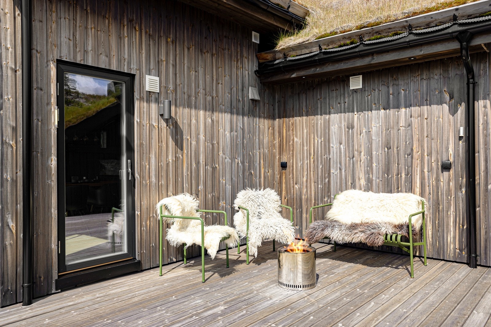 Lun og solrik uteplass med terrassedør inn til stue/kjøkken. Rundt hjørnet til høyre er det en sidedør inn til garasjen hvor man i tillegg kan lagre ski og ved Galleribilde