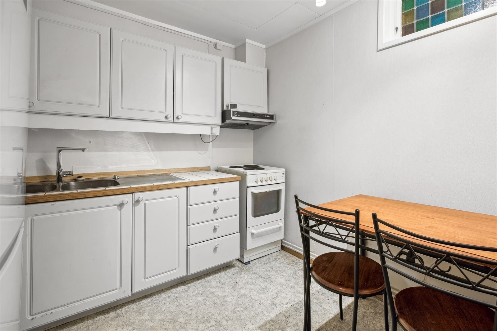 Kjøkkenet ligger i eget rom og er godkjent som gang. Det er enkel innredning med profilerte fronter og flislagt benkeplate med nedfelt kum. Galleribilde