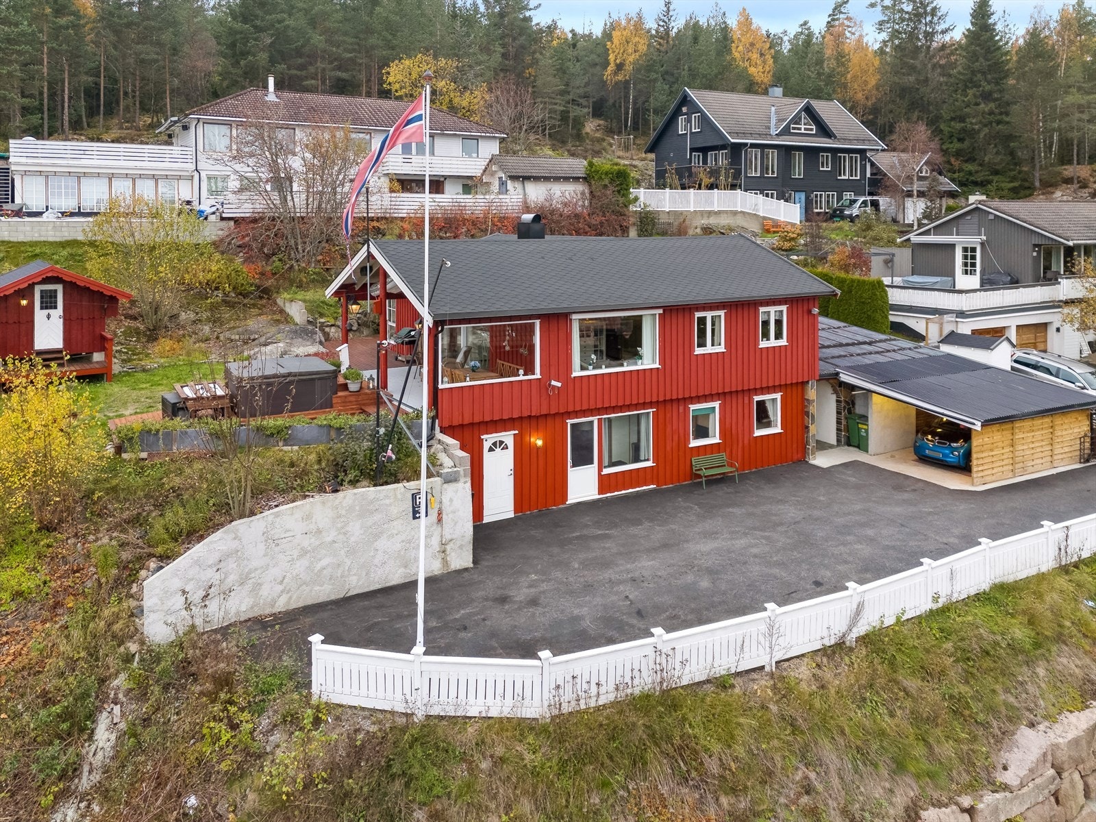 Det er garasje med tilliggende carport og to stk. elbil-ladere på murvegg. Galleribilde
