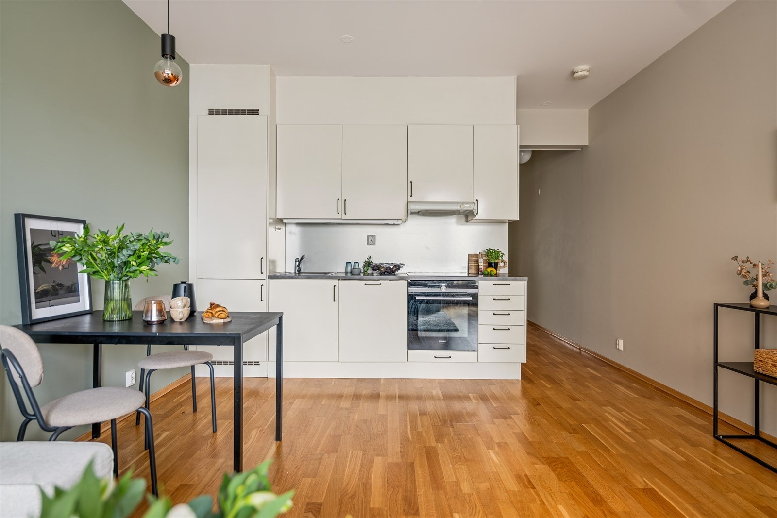 Den åpne løsningen mellom stue og kjøkken gir et sammenhengende og luftig oppholdsrom, samtidig som rommet naturlig deles inn i to funksjonelle soner. Galleribilde