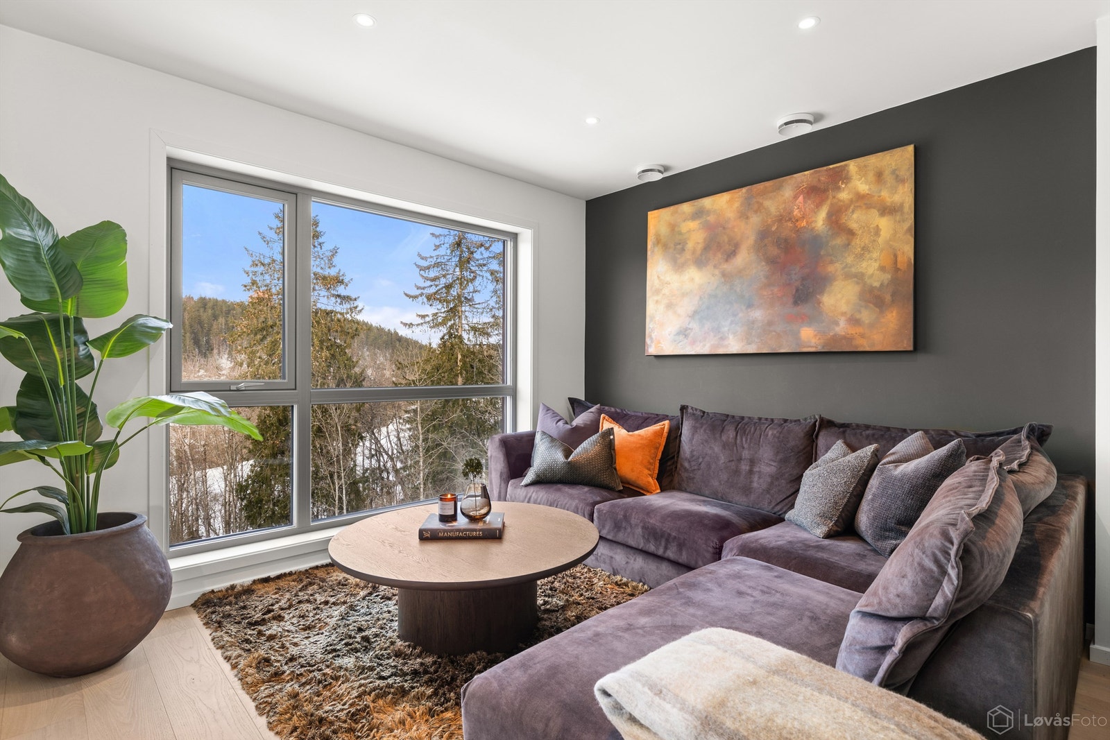 En fondvegg i en mørkere nyanse skaper en lun og definert sone i stuen. Galleribilde