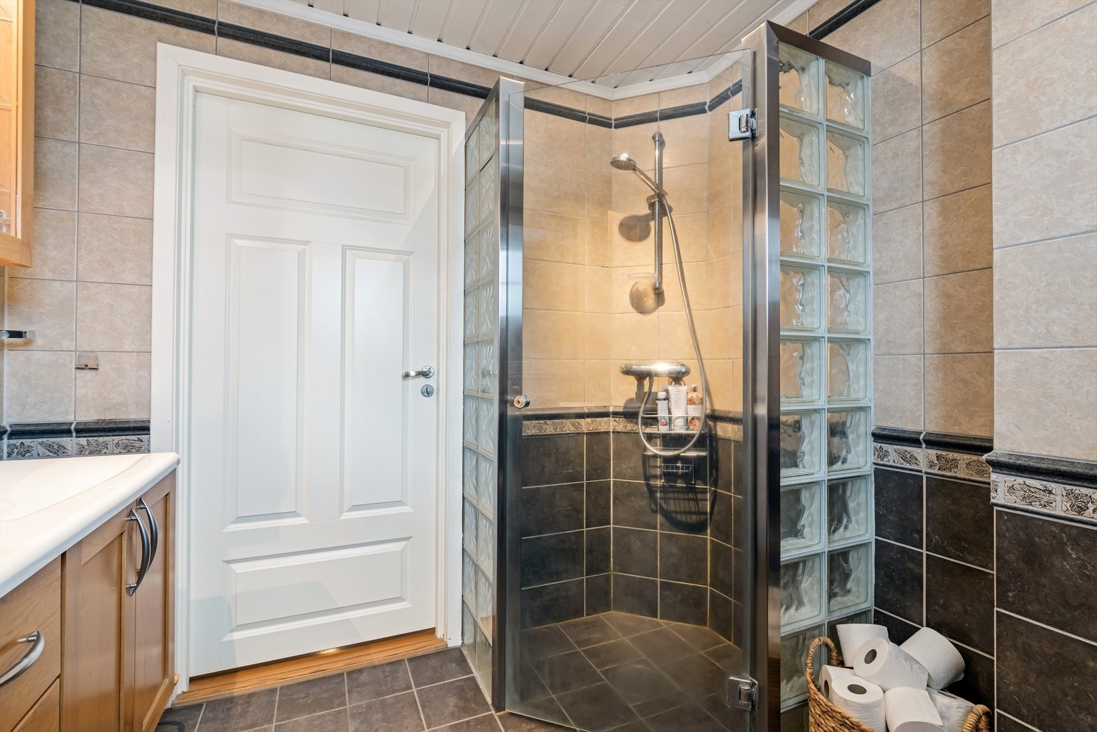 Baderomsinnredning med benkeskap og veggskap med profilerte fronter. Innfliset speil over servant. Dusjhjørne med vegger i glassbyggerstein. To servanter i helstøpt plate. Galleribilde