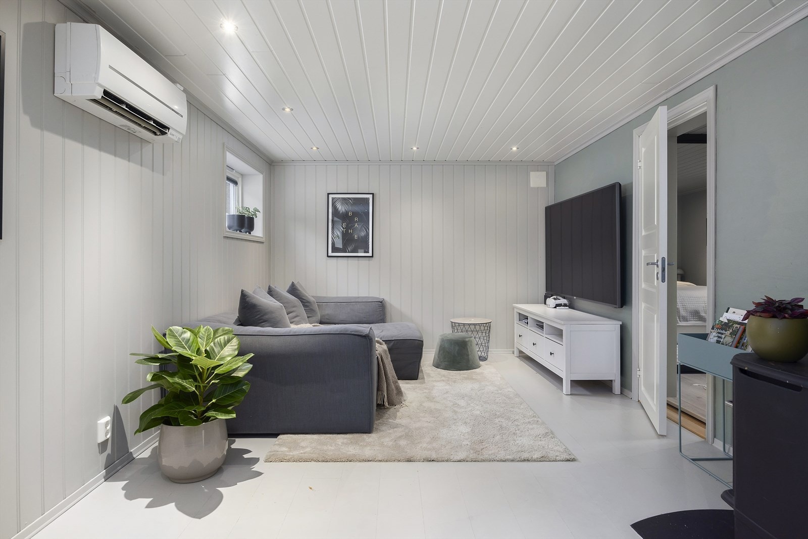 Lyst og fint rom benyttet som kjellerstue, med varmepumpe og peisovn. Galleribilde