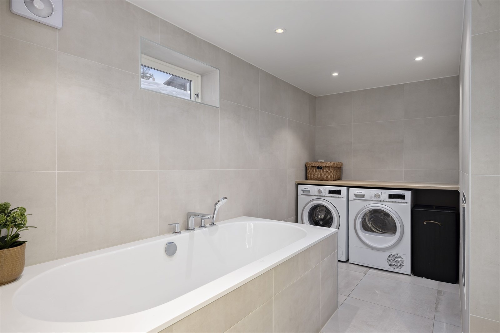 Kombinert bad og vaskerom med egne soner og opplegg for både vaskemaskin og tørketrommel. Galleribilde
