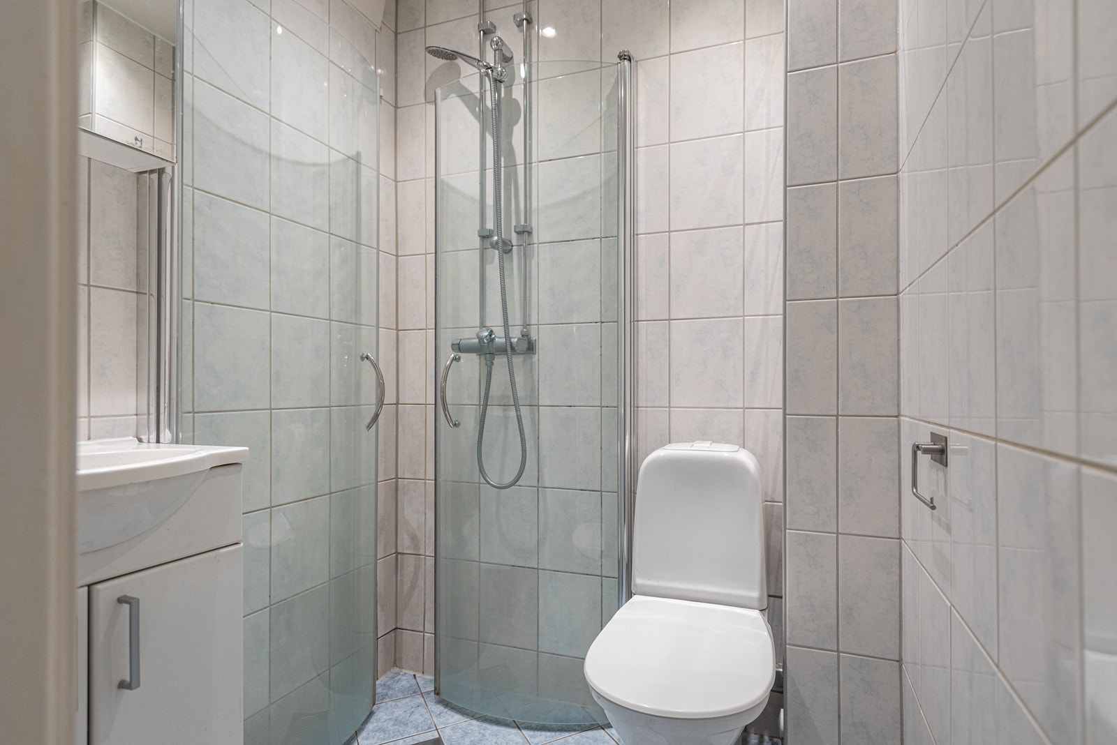 Badet er innredet med innfellbare dusjdører, wc og servantskap med ett greps blandebatteri fra Oras Galleribilde