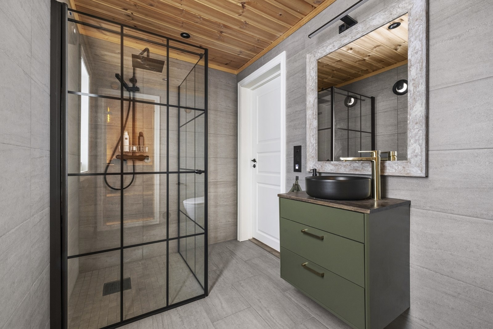 Badet er innredet med veggmontert toalett, glassvegger med dusjnisje, samt servantinnredning med skuffer og speil med overlys. Det er elektrisk ventilasjon. Galleribilde