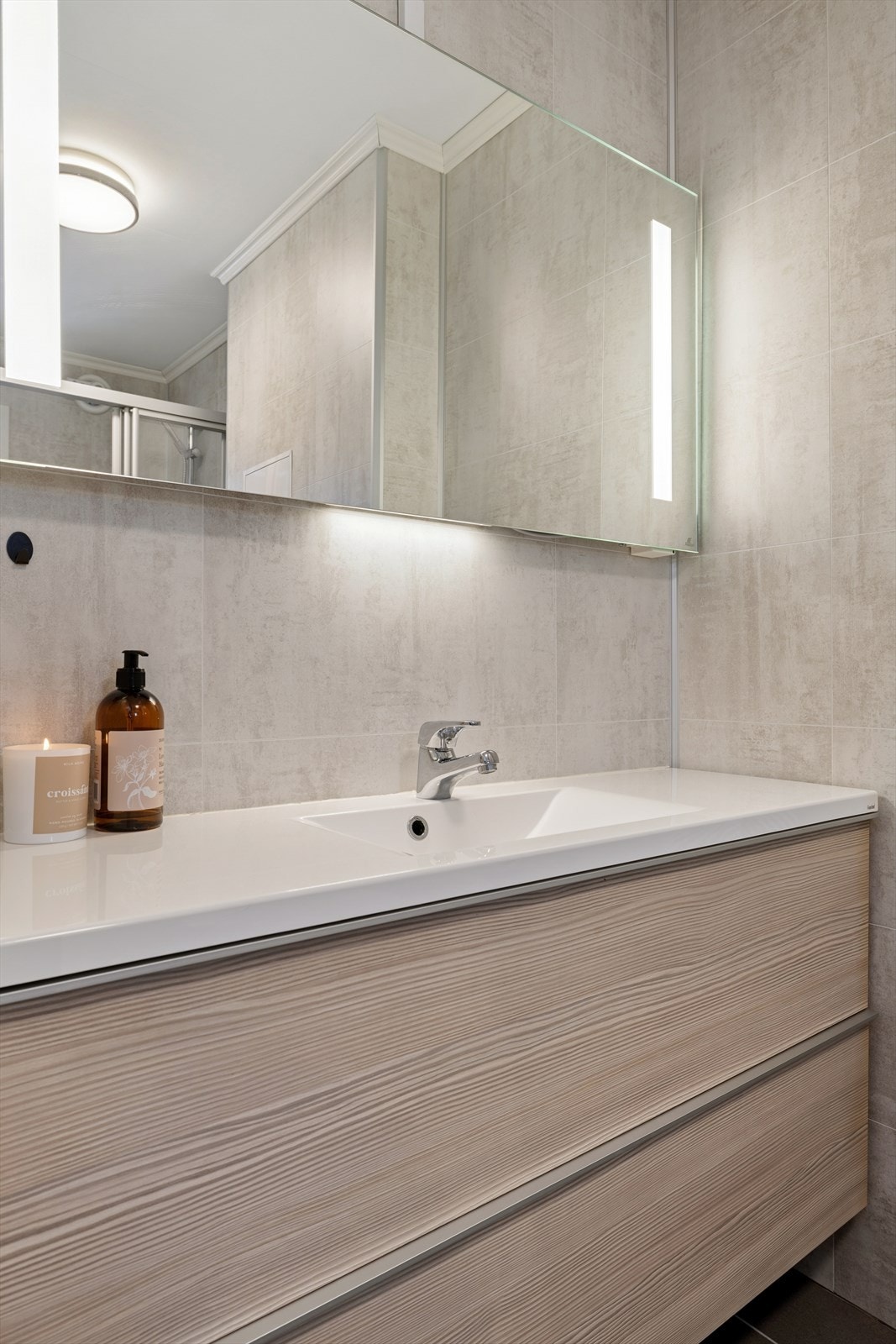 Bad med heldekkende servant, underskap, vegghengt toalett og dusjsone med skyvedører. Galleribilde