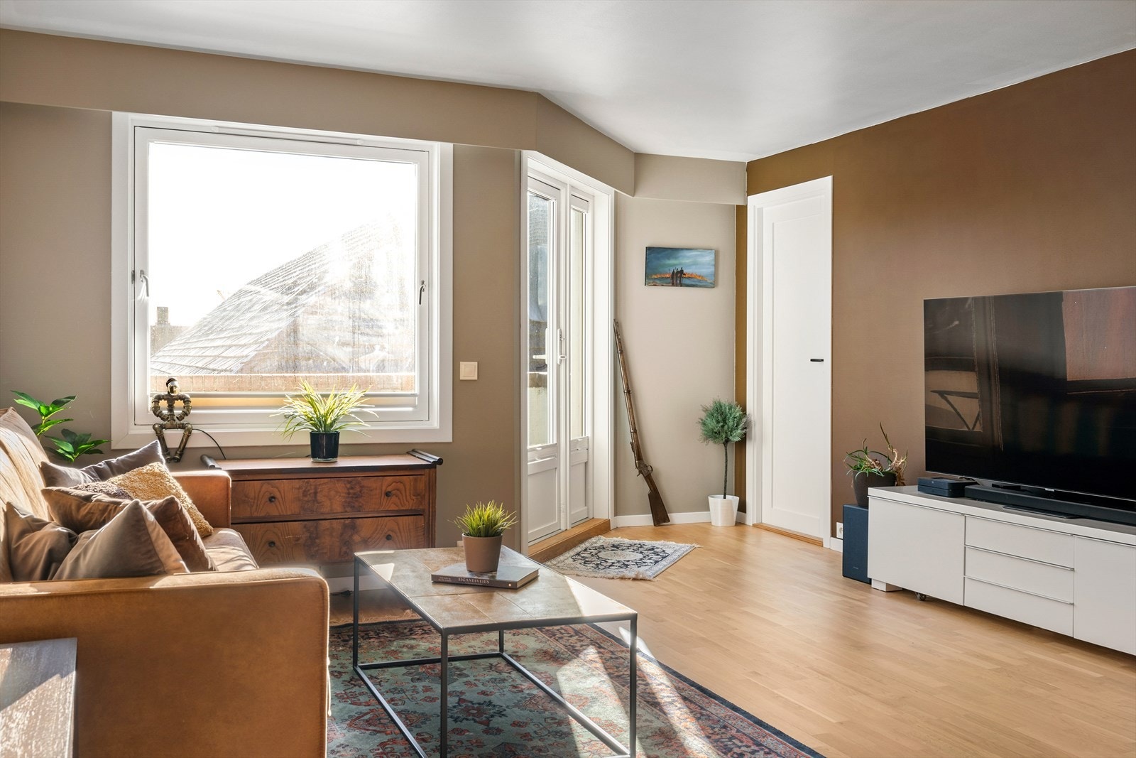 Stuen er lys og luftig med store vindusflater som slipper inn rikelig med dagslys. Rommet har en utforming som gir god møbleringsfrihet, med plass til både en sofagruppe, TV-møblement og spisebord. Galleribilde