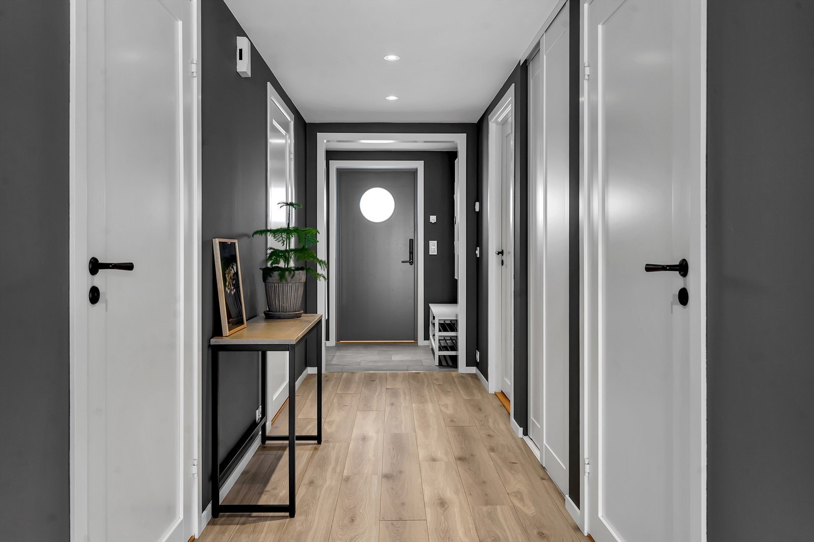 Romslig gang med parkettgulv og moderne fargevalg som skaper en helhetlig og stilren atmosfære. Galleribilde