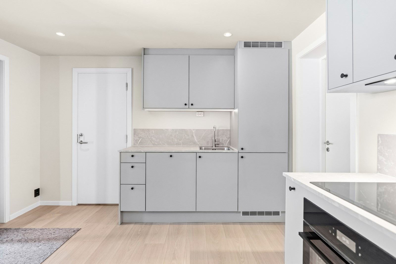 Skapene har glatte, fabrikklakkere fronter, og det er montert benkeplate i laminat. I tillegg er det montert integrerte hvitevarer. Galleribilde