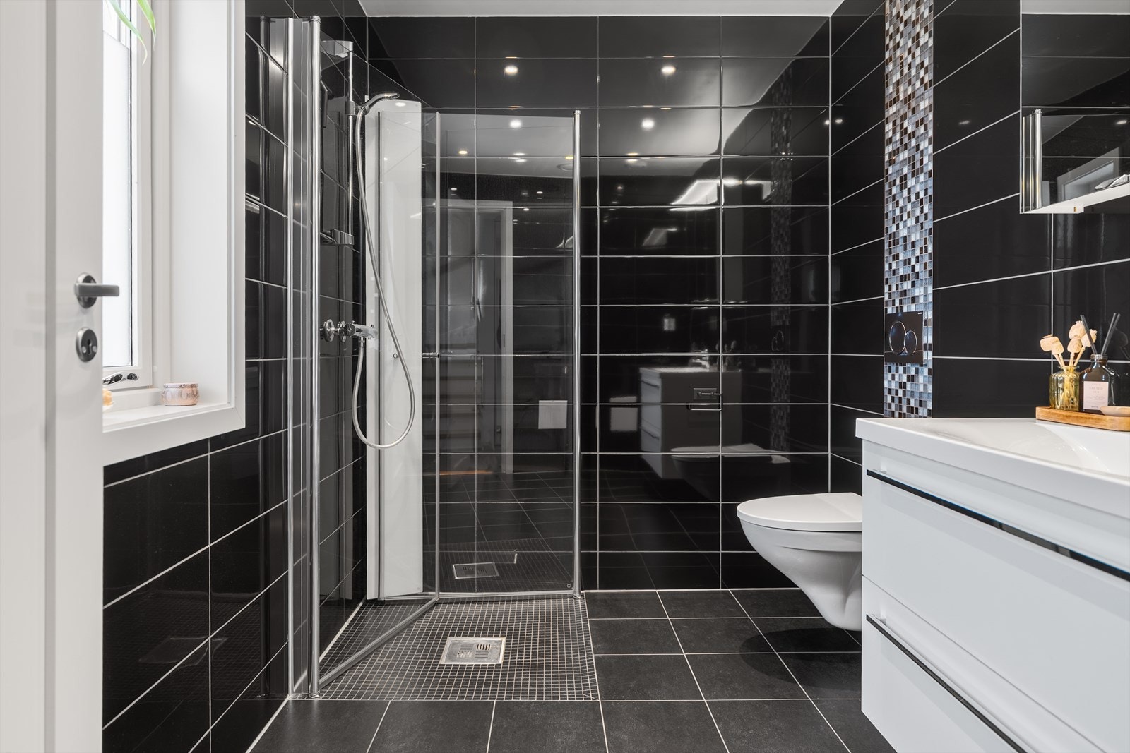 Delikat og stilrent baderom med et moderne uttrykk, utført med sorte fliser som gir rommet et tidløst preg. Galleribilde