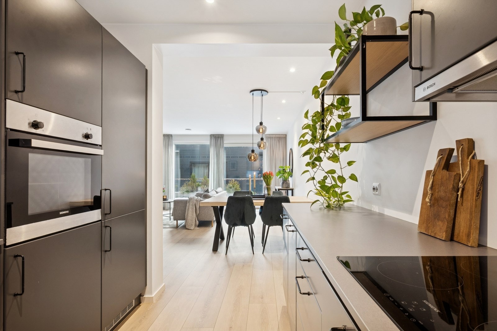 Kjøkkenet har en moderne Drømmekjøkken-innredning fra 2020 med mørke, glatte fronter, laminert benkeplate og nedfelt oppvaskkum i svart kompositt. Galleribilde