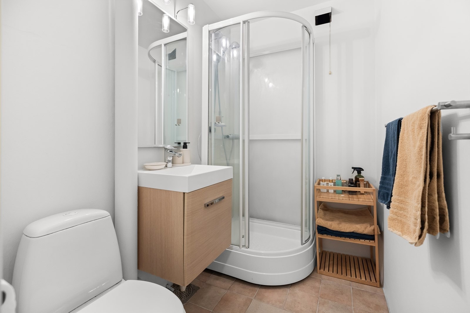 Pent baderom med malt betong på vegger og fliser på gulv med gulvvarme. Galleribilde