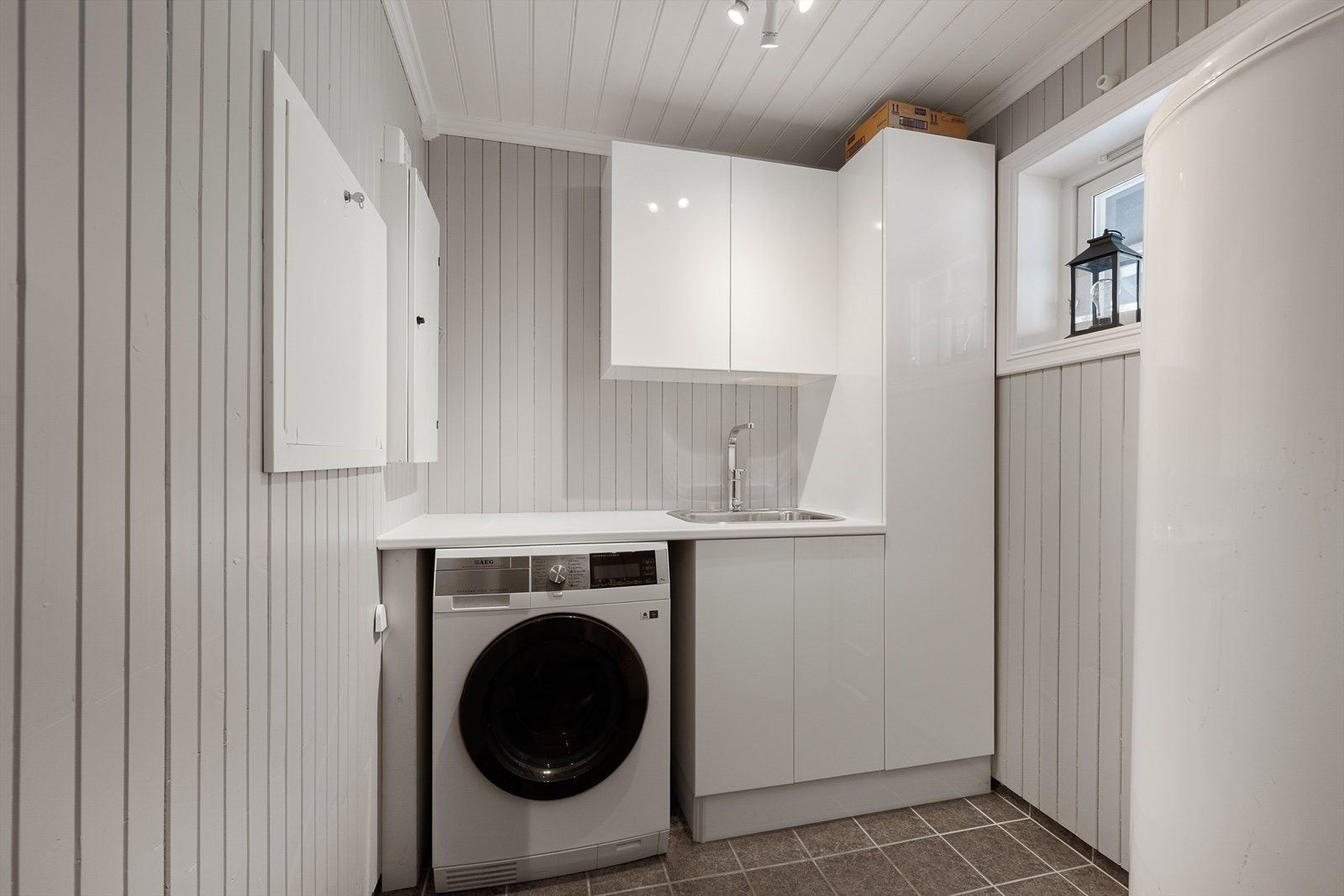 Praktisk vaskerom med opplegg for vaskemaskin, utslagsvask og god skapplass. Galleribilde