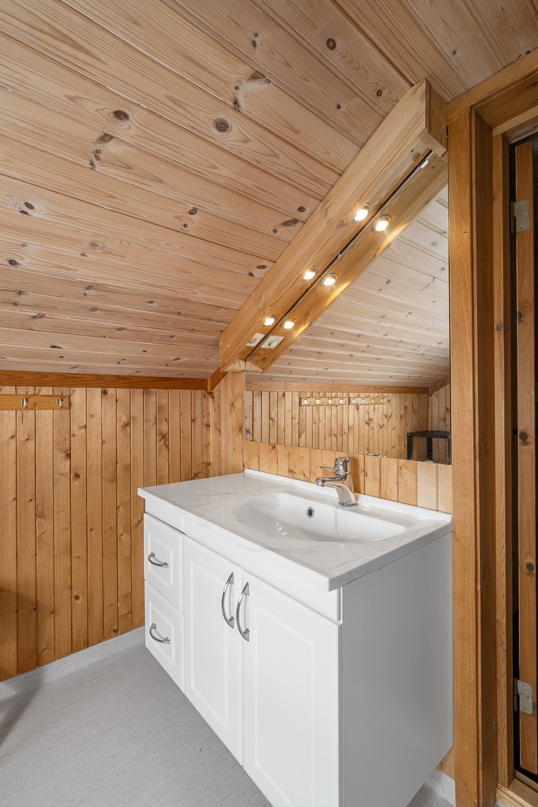 Servant med underskap og speil med belysning kompletterer badet på hemsen. Galleribilde