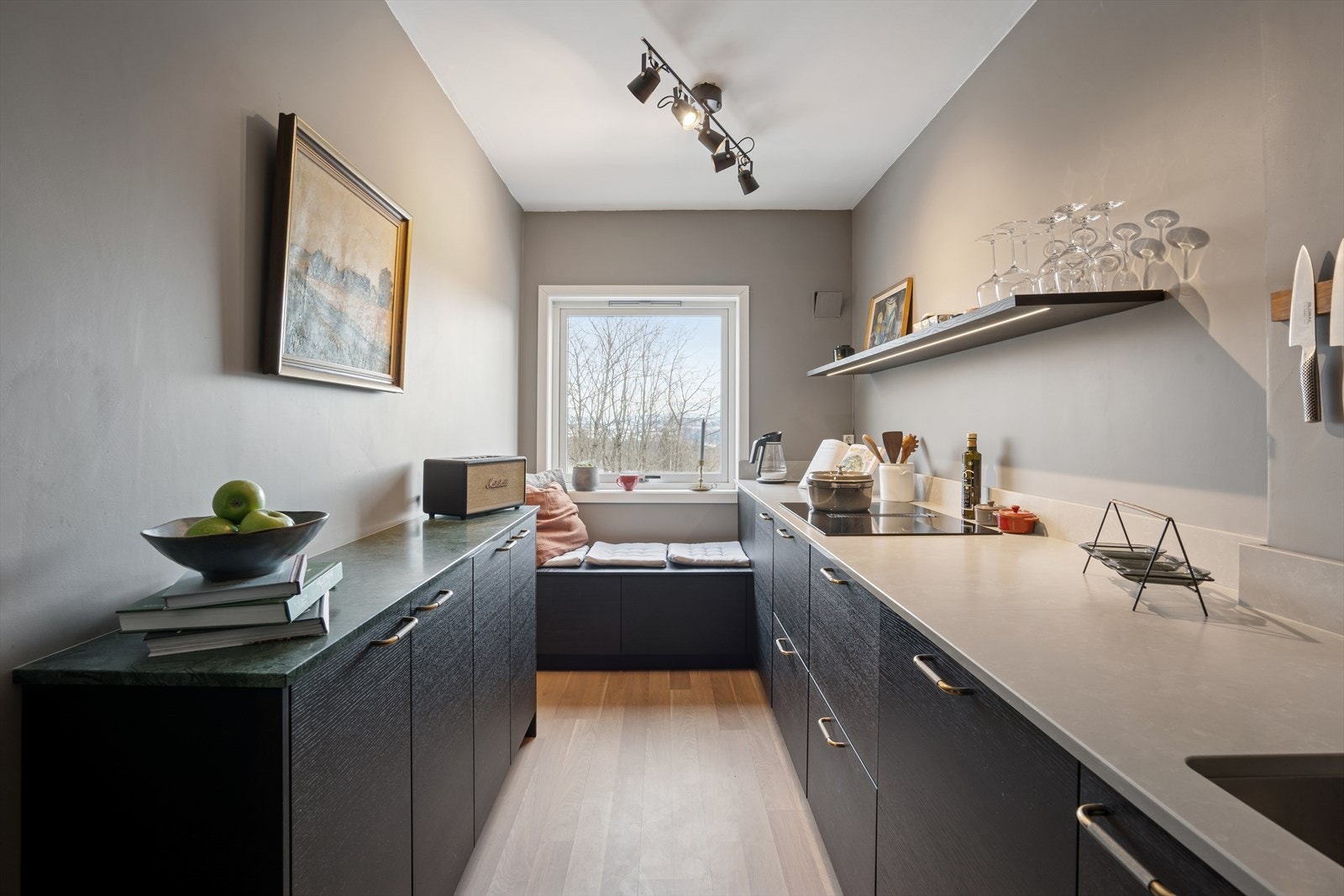 Kjøkkenet fra 2022, levert av Drømmekjøkkenet er et virkelig blikkfang.
Her snakker vi eksklusiv, moderne kvalitet, med slette fronter i mørkbeiset ask, solid steinkompositt på benk og en rålekker grønn marmorbenk som signaturdetalj. Galleribilde