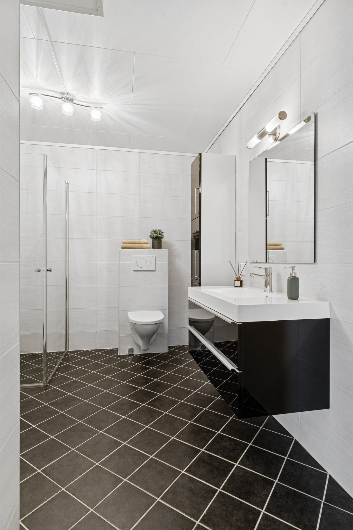 Baderommet er stilrent innredet med dusjhjørne, vegghengt toalett og servant. I tillegg er det et ekstra skap for oppbevaring. Galleribilde