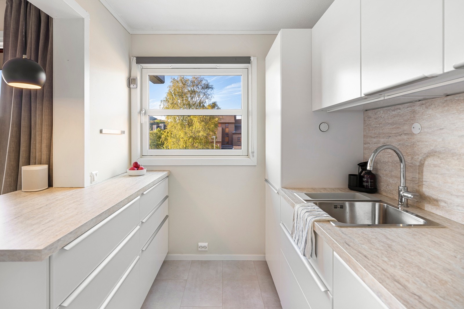 Innredningen har hvite, slette fronter som gir et tidløst uttrykk, kombinert med laminatbenkeplate og dobbel oppvaskkum. Galleribilde