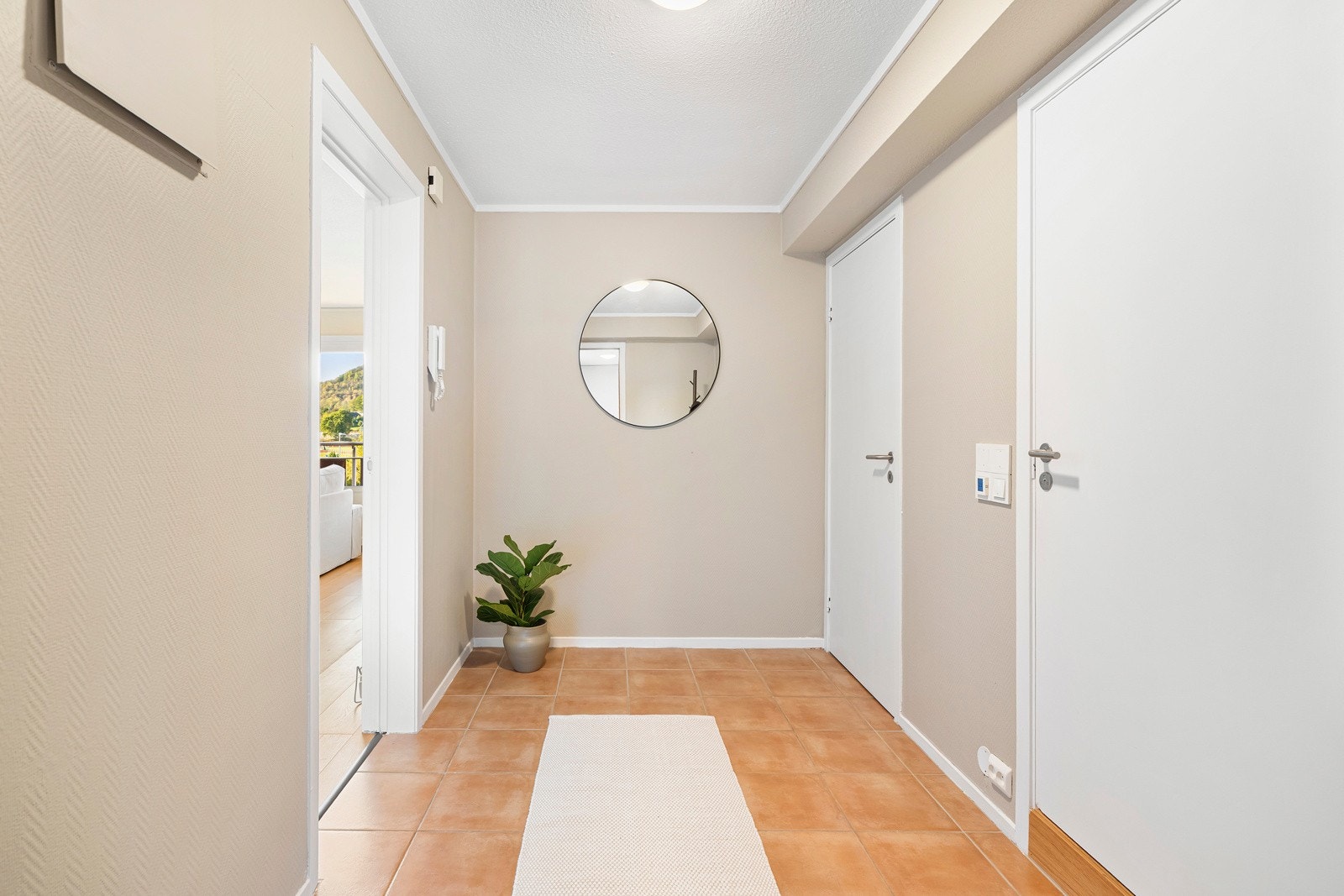 Innenfor døren ønskes du velkommen av en innbydende gang med flislagt gulv og vegger malt i en moderne, beige tone. Galleribilde