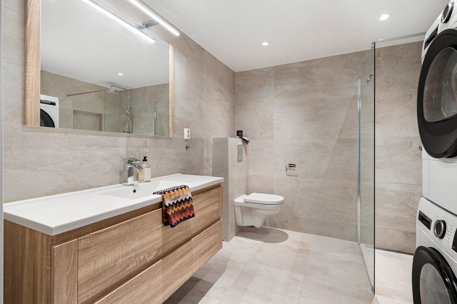 Både gulv og vegger er kledd med store, duse fliser som gir et tidløst og stilrent preg. Galleribilde