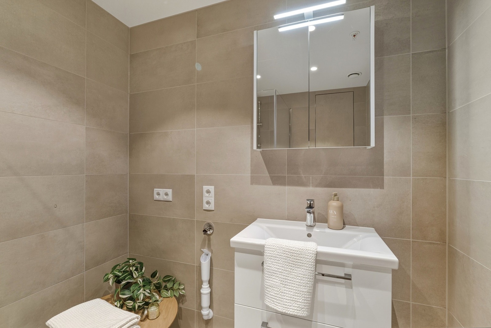 Innredning med heldekkende servant, veggmontert toalett, dusjvegger/hjørne og opplegg for vaskemaskin. Galleribilde