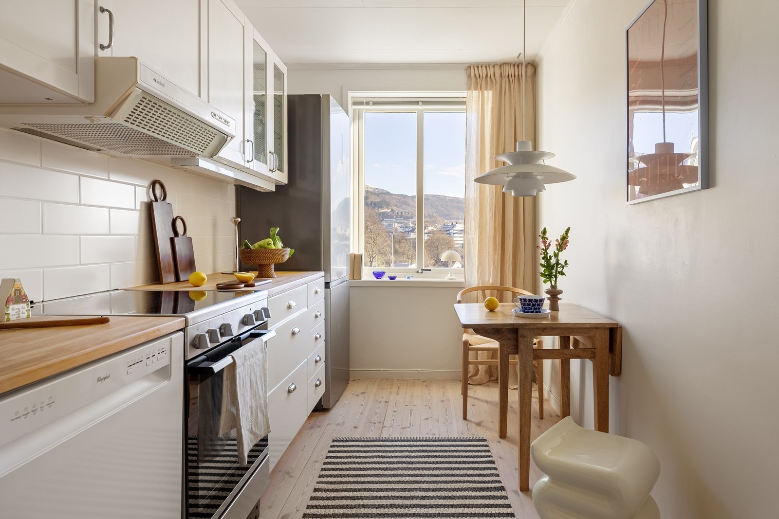 Heltre benkeplate og flislagt vegg gir kjøkkenet varme og karakter innenfor en smart planløsning. Galleribilde