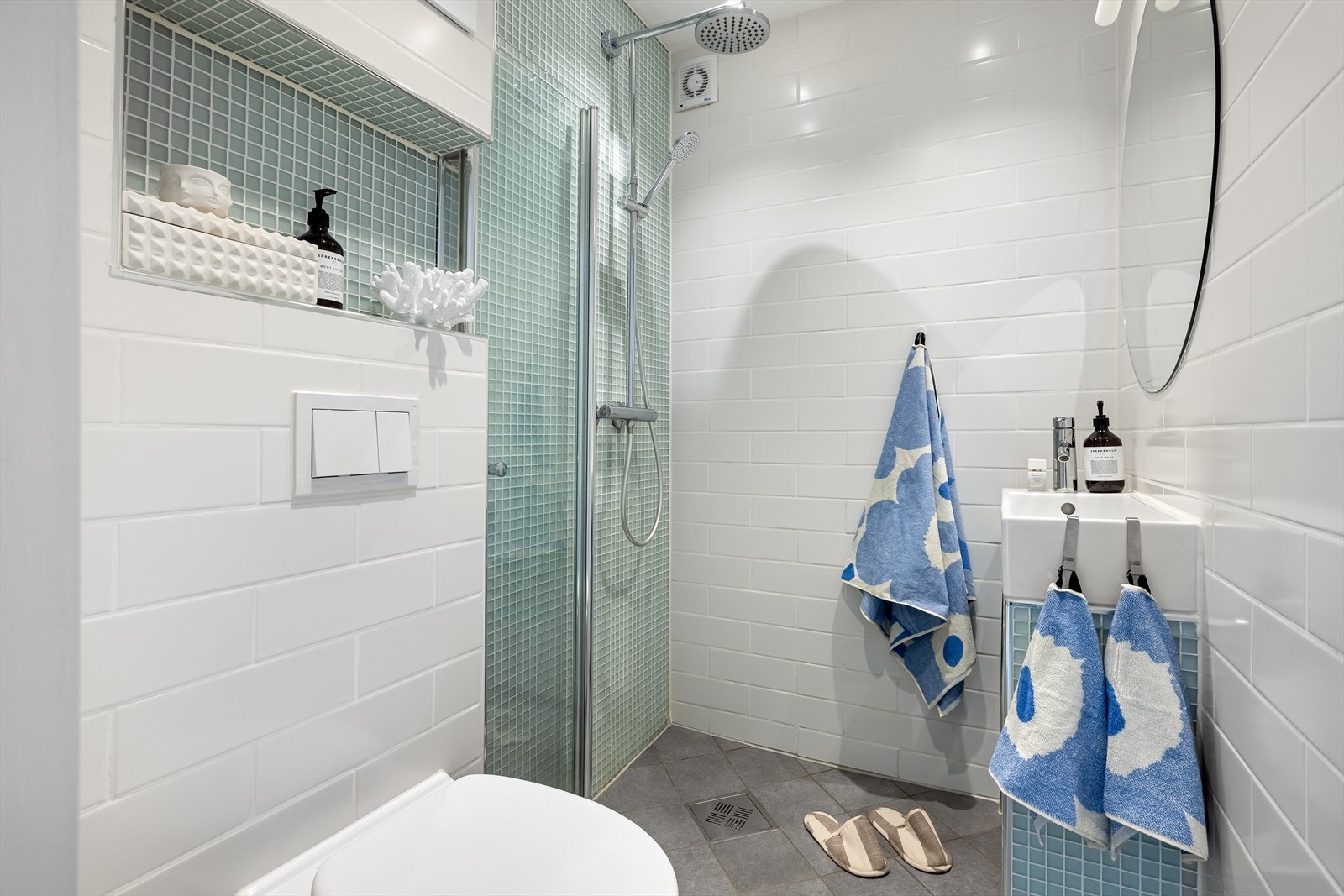 Flislagte overflater og praktiske løsninger gjør badet både stilrent og funksjonelt. Galleribilde