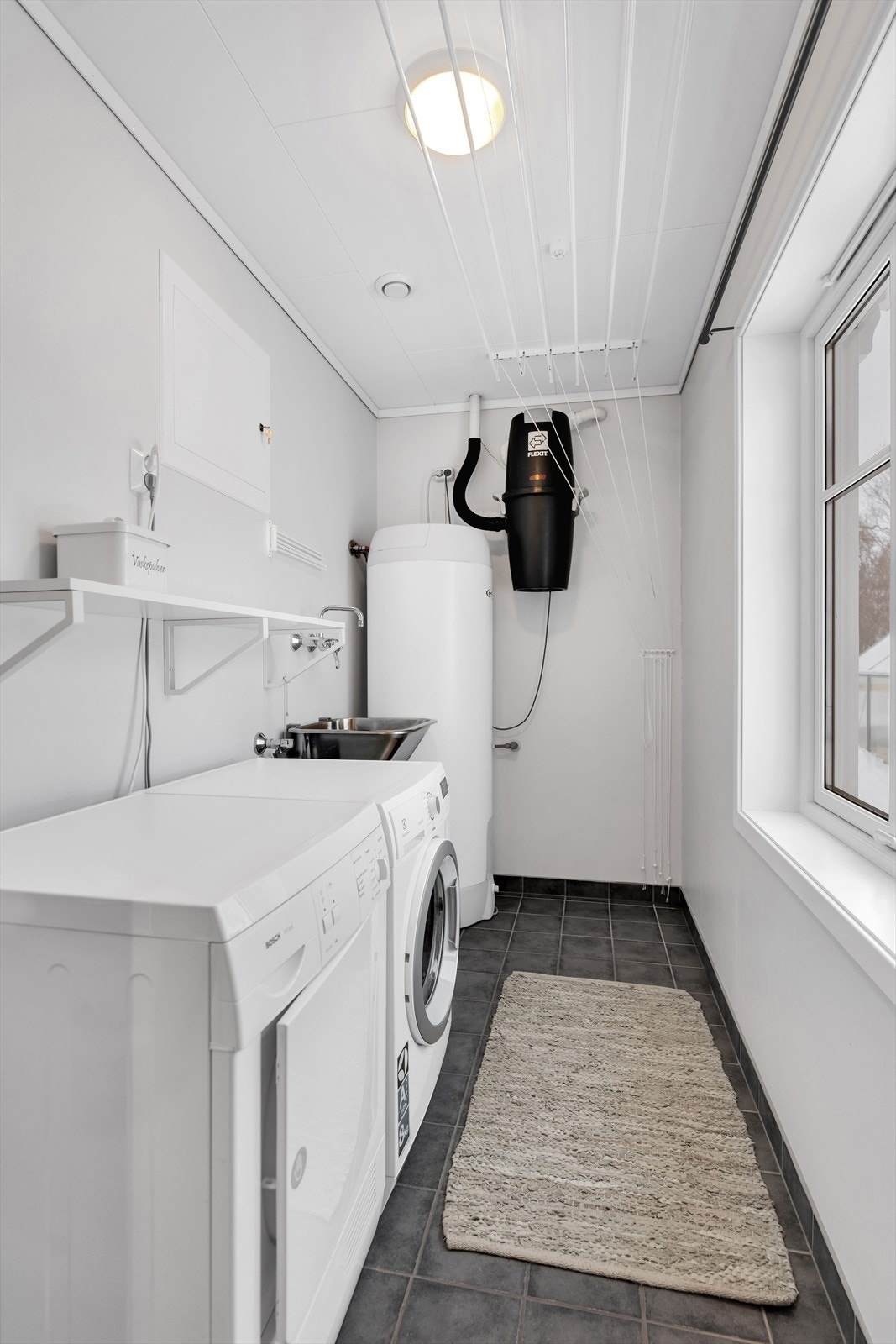 Vaskerom med flislagt gulv, samt opplegg for vaskemaskin og tørketrommel. Galleribilde