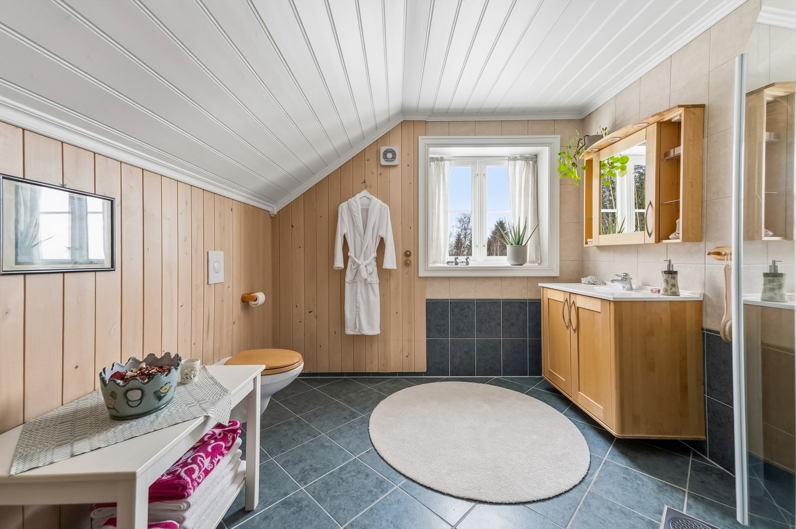 Flislagt bad kombinert med trepanel, toalett og dusj - gir et fint og helhetlig uttrykk. Galleribilde