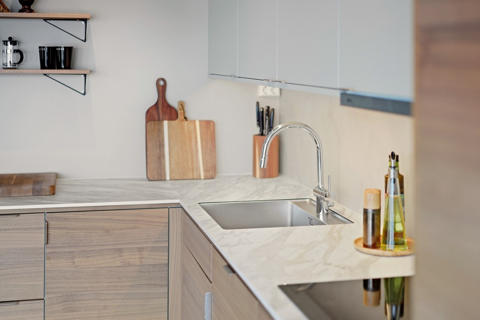 Det er valgt en kombinasjon av valnøttfronter og malte fronter i dempet beige på kjøkkenet Galleribilde