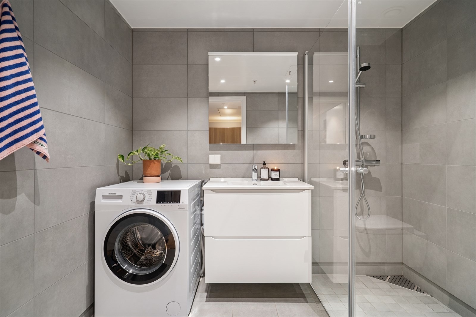 Innredningen består av speil, servant med seksjon, dusjhjørne, veggmontert toalett og opplegg for vaskemaskin. Galleribilde