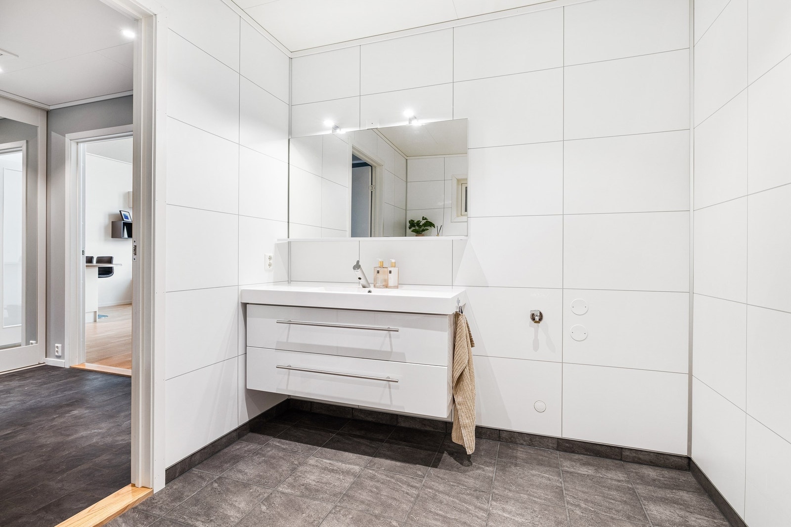 Pent flislagt bad med varmekabler i gulv og speil med belysning Galleribilde