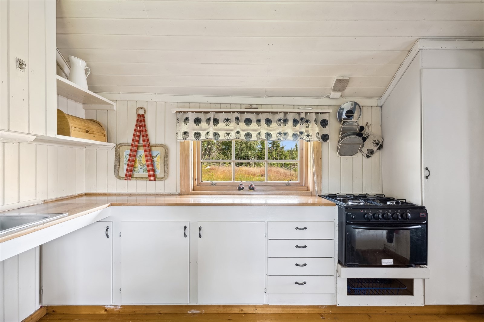 Innredningen består av underskap, skuffer og et høyskap. Det er plassbygde vegghyller og benkeplate med vaskekum med gråvann til terreng. Galleribilde