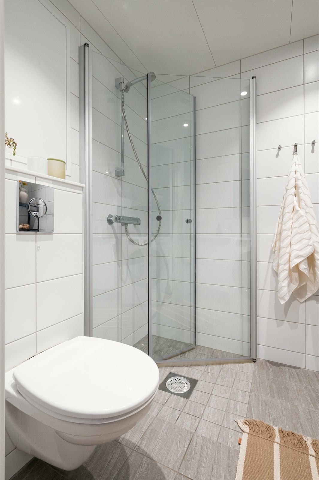 Badet er innredet med heldekkende servant på underskap, speil med belysning, vegghengt toalett og dusj med dusjvegger i herdet glass. Galleribilde