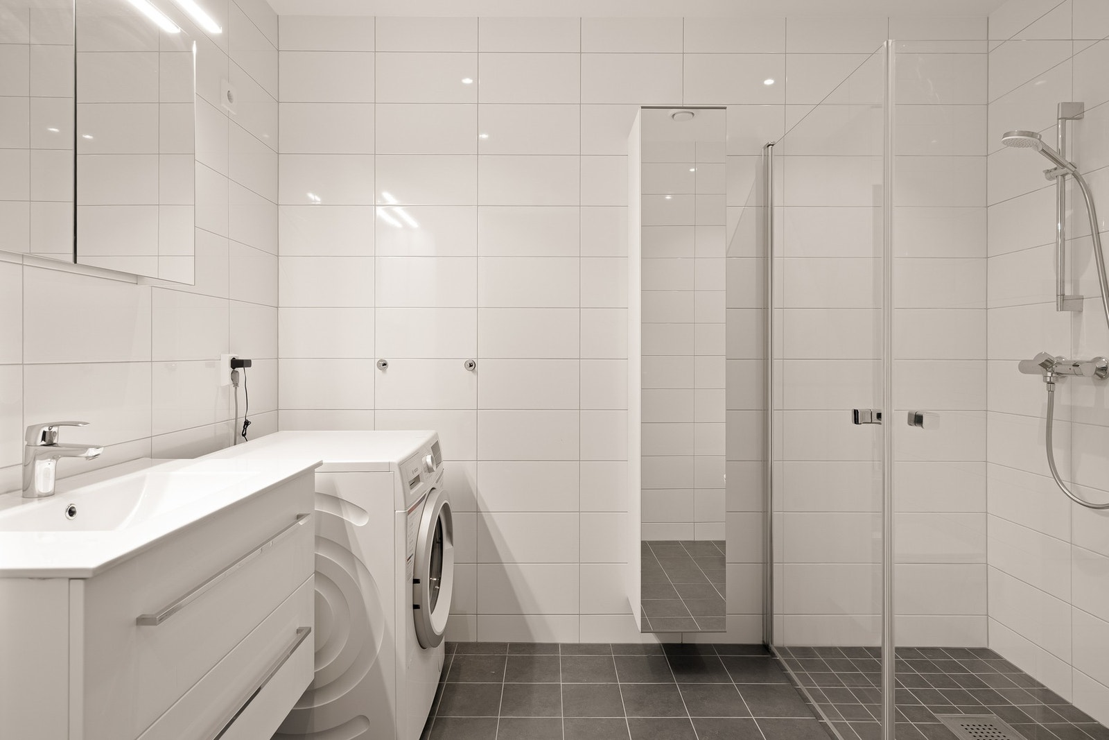 Badet i første etasje har innredning med nedfelt servant, veggmontert toalett, dusjvegger/hjørne og opplegg for vaskemaskin. Galleribilde