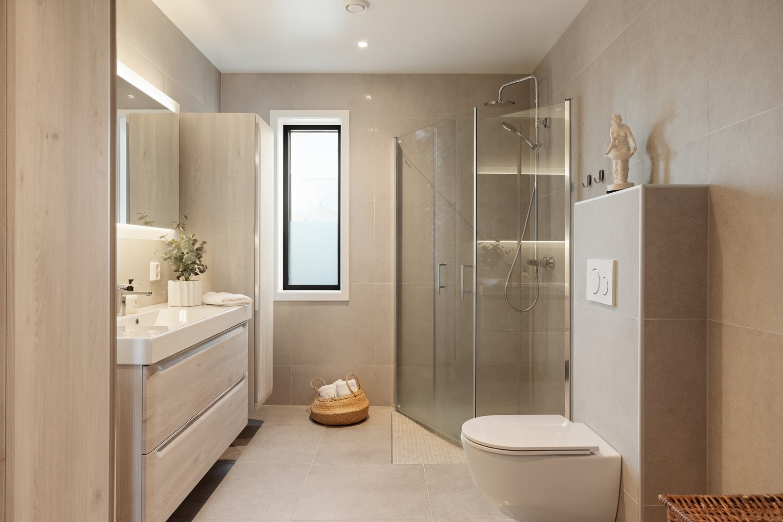 Badet i denne etasjen har dusjsone med garnityr og glassdører, baderomsinnredning med heldekkende dobbel vask, vegghengt toalett og ettgreps blandebatteri Galleribilde