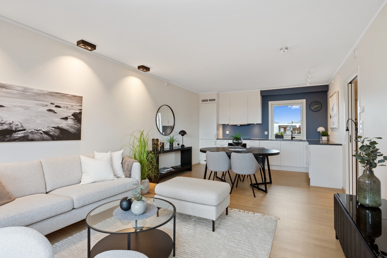 Moderne selveierleilighet med oppgraderte kjøkkentilvalg og stilfulle dim-to-warm downlights. Stuen har en gjennomgående fargepalett med hovedsakelig hvite vegger og sorte detaljer. Blågrå kontrastvegg på kjøkkenet. Galleribilde