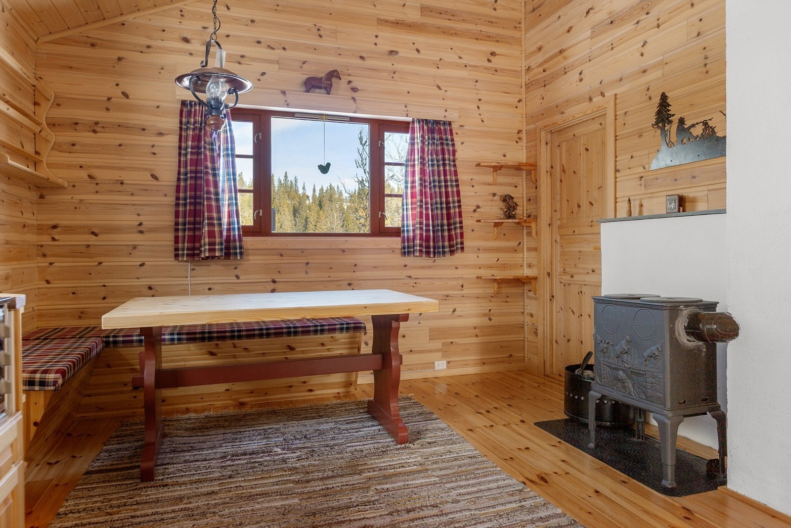 Oppholdsrommet har raustet himling og liten vedovn som gir lun og god varme til hytta, i tillegg til oppvarming med strøm. Galleribilde