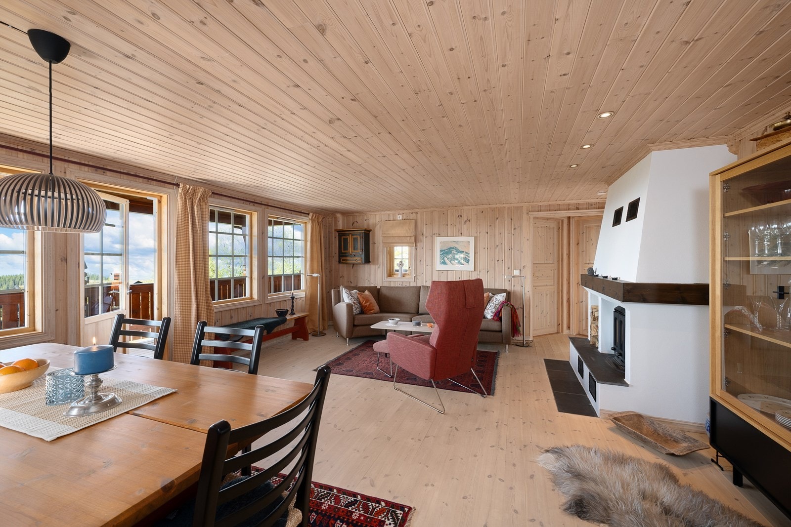 Det kommer rikelig med naturlig lys inn i hytta gjennom store vindusflater. Gjennomført og helhetlig stil med tregulv og panelte vegger og tak. Galleribilde
