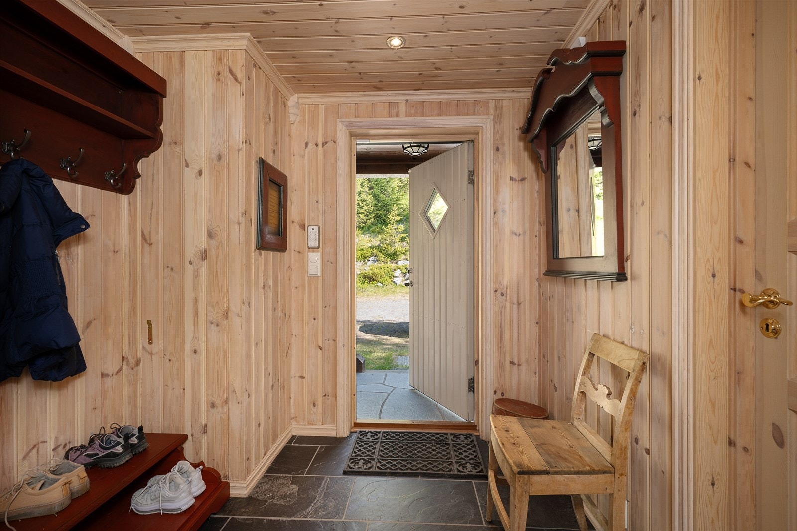 Det er et lite overbygg over inngangspartiet. Gangen er romslig og praktisk. Fliser på gulv med varmekabler. Galleribilde